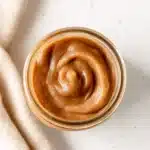 Slow Cooker Apple Butter – Easy & Delicious Recipe 20 Top-down view of a glass jar filled with creamy, swirled slow cooker apple butter on a rustic table.