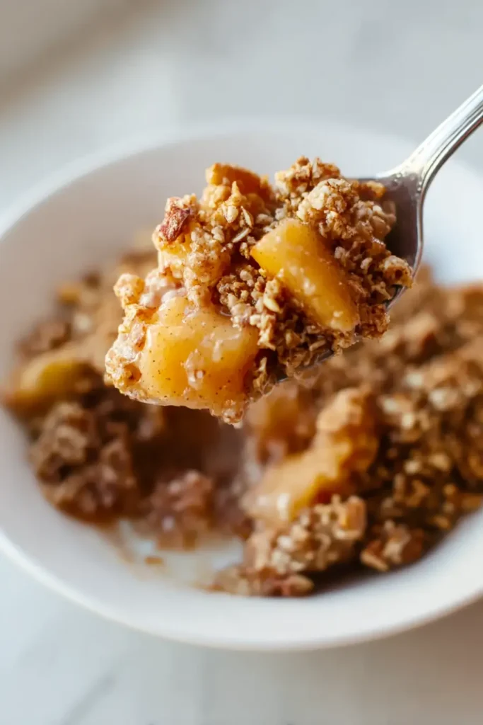 Spoonful of healthy breakfast apple crumble with apples and golden topping