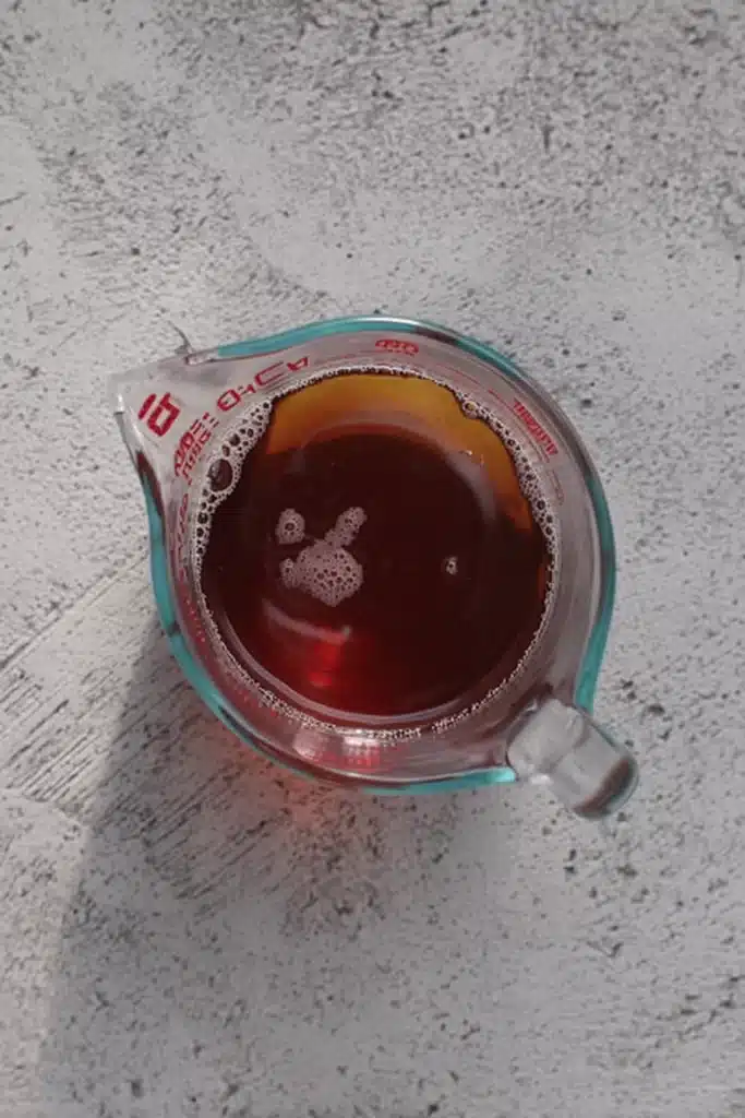 Strained brewed tea in glass measuring cup for apple iced tea