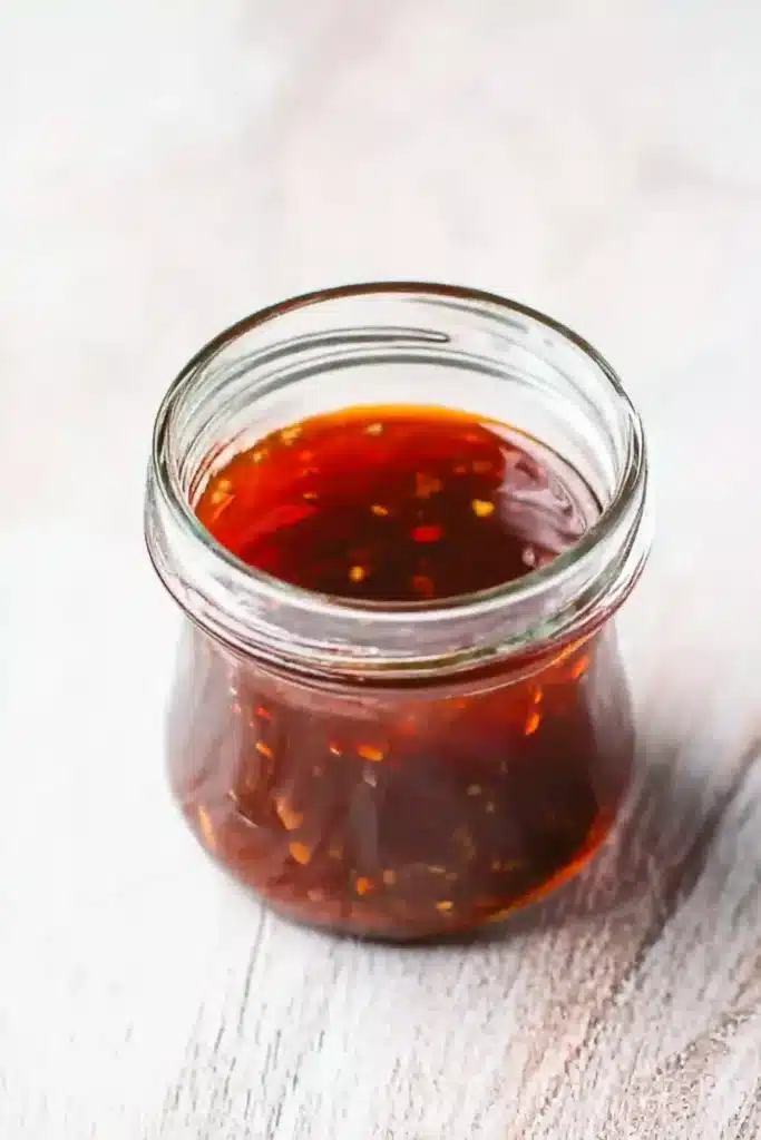 Homemade sticky sesame sauce in a glass jar on a marble background