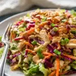 Colorful Whole30 Chinese Chicken Salad with sesame dressing, crunchy vegetables, and fresh herbs on a white plate