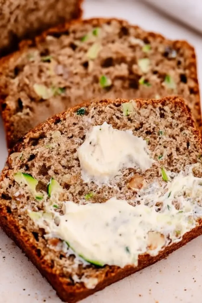 5-Ingredient Spinach Parmesan Zucchini Noodles styled as zucchini bread slice with creamy butter spread on a beige surface