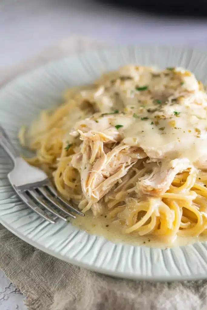 Creamy crockpot angel chicken over pasta on ceramic plate with fork