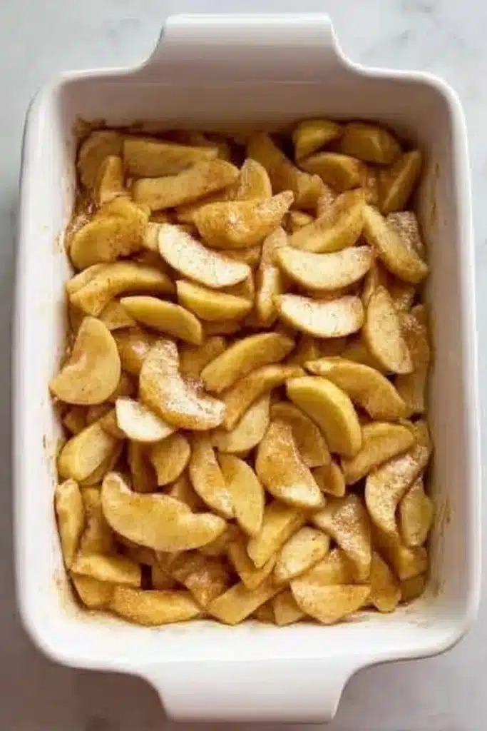 apple cobbler filling in a white baking dish before topping is added