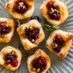 Baked Cranberry Brie Bites – Quick & Festive Favorite 12 Baked Cranberry Brie Bites arranged on a plate with flaky pastry and cranberry filling