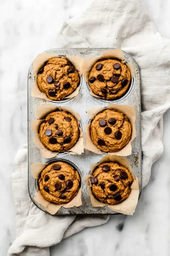 Pumpkin chocolate chip protein muffins baked in a rustic muffin tin