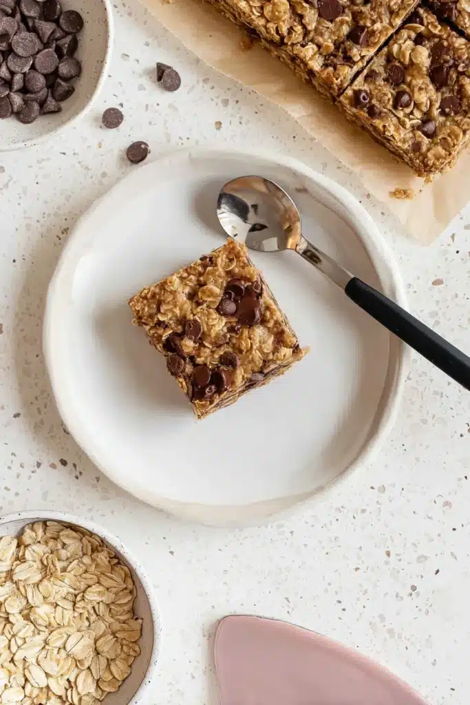 Banana Oatmeal Bars | Quick, Easy & Wholesome Snack 10 Banana oatmeal bar on white plate with spoon and chocolate chips