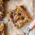 Banana Oatmeal Bars | Quick, Easy & Wholesome Snack 11 Banana oatmeal bars with chocolate chips on parchment paper, soft and chewy texture