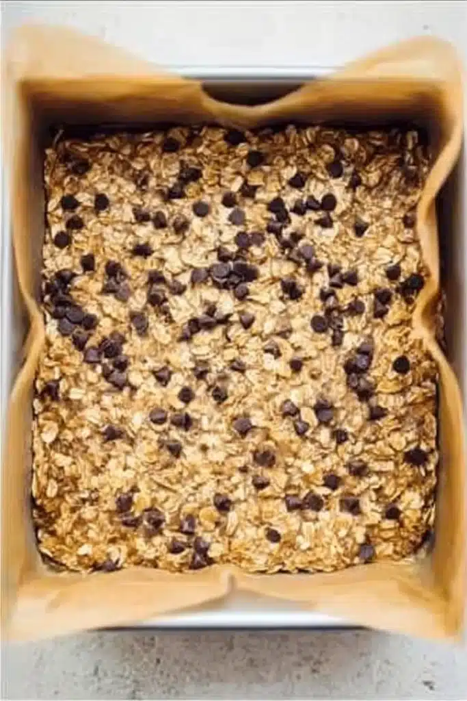 Unbaked banana oatmeal bars in square pan with chocolate chips