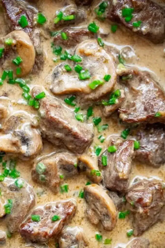 Close-up of creamy beef stroganoff sauce with beef, mushrooms, and chives