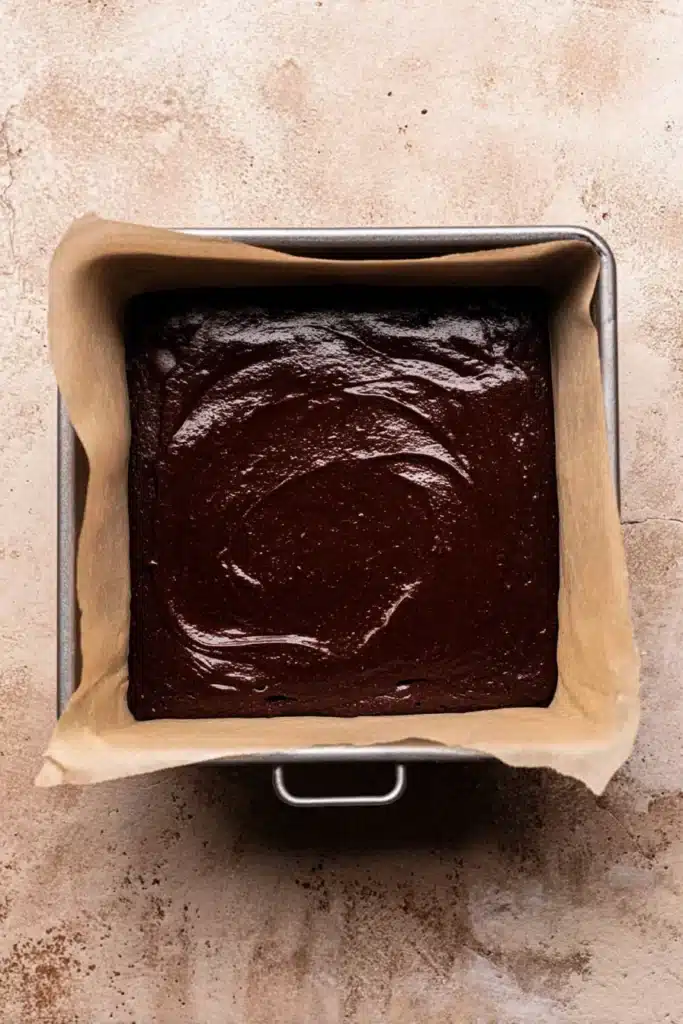 Brownie batter spread in square pan for Halloween brownies