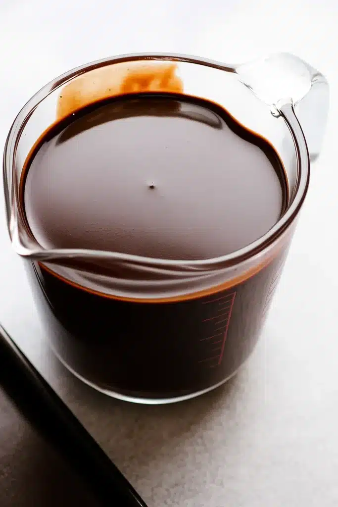 Fresh chocolate mirror glaze in a glass measuring cup