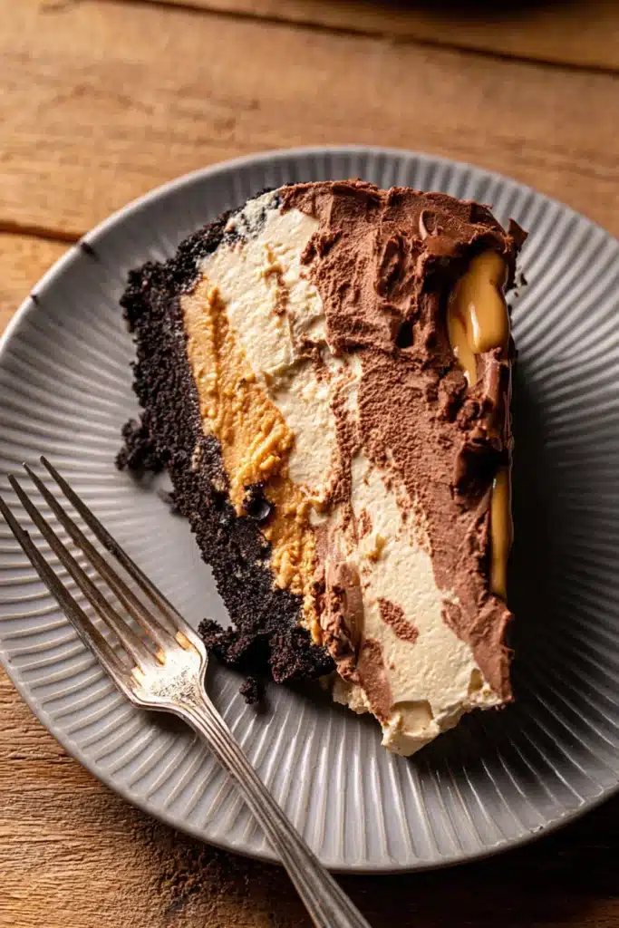 Top view of a chocolate peanut butter pie slice with Oreo crust and fork on plate