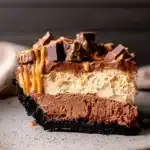 Slice of no-bake chocolate peanut butter pie with Oreo crust and candy topping