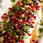 Christmas baked salmon topped with dill sauce, cranberries, pomegranate, and almonds