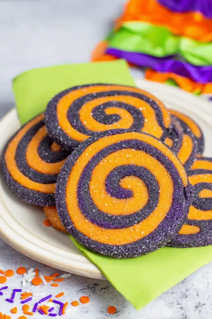 Colorful Halloween pinwheel cookies with orange and black spirals on white plate