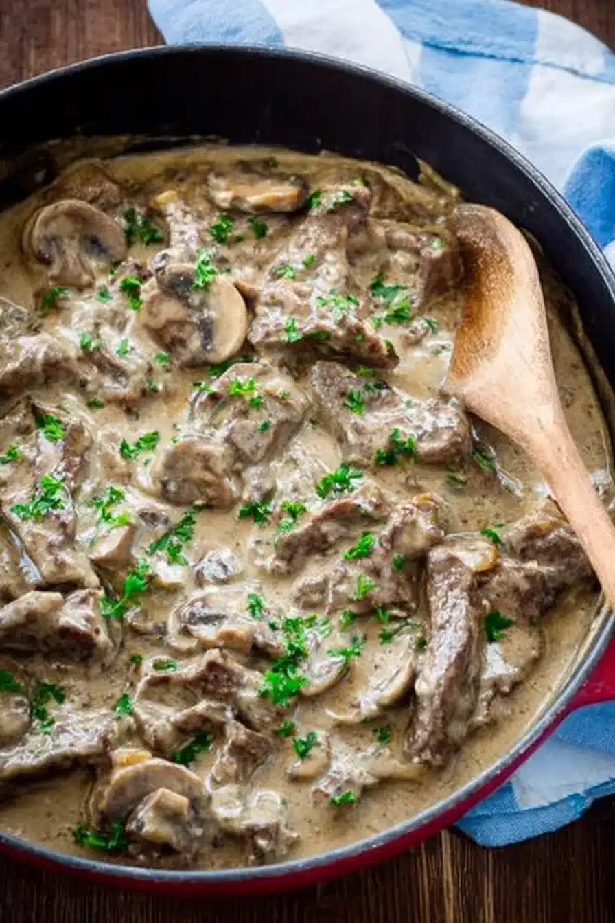 Creamy beef stroganoff with mushrooms and herbs in a skillet
