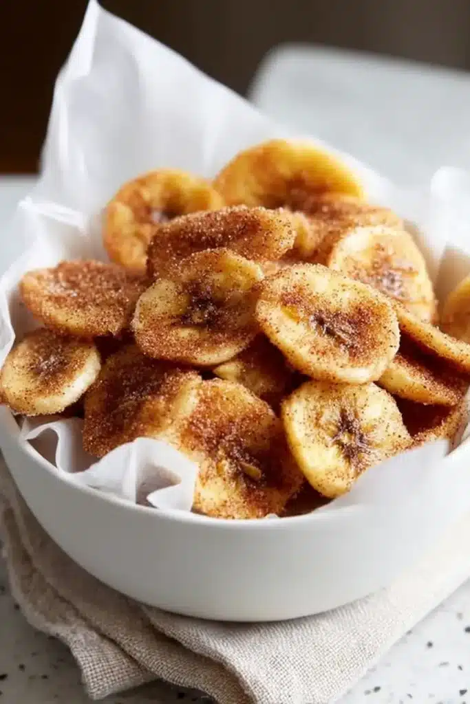 Easy Cinnamon Air Fryer Banana Chips – Quick & Amazing 11 Sweet Cinnamon Air Fryer Banana Chips in white bowl with parchment paper