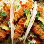 Crunchy chicken taco fingers in tortillas with slaw, avocado, and sriracha