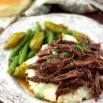 Easy Mississippi pot roast with butter and peperoncini peppers on a rustic wooden table