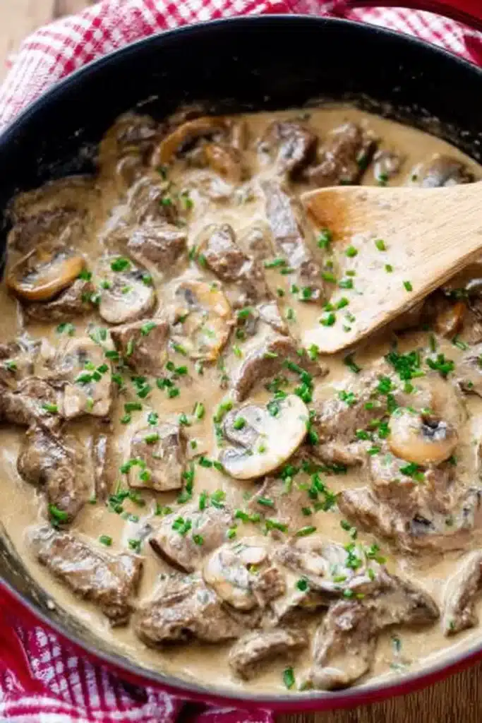 Finished creamy beef stroganoff in skillet with mushrooms and chives