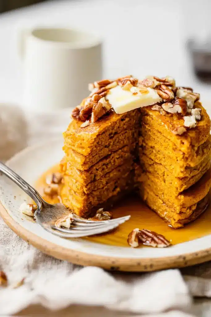 Stack of healthy pumpkin pancakes sliced to show fluffy inside