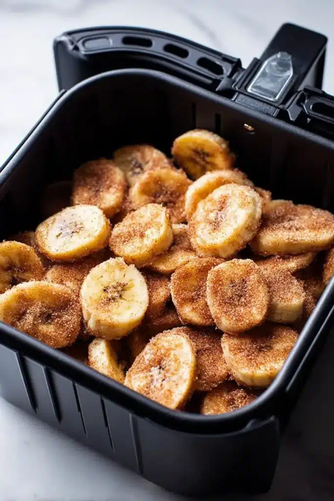 Sweet Cinnamon Air Fryer Banana Chips in black basket on marble surface
