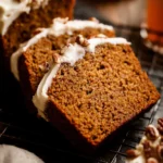Frosted pumpkin bread topped with cream cheese frosting and chopped pecans