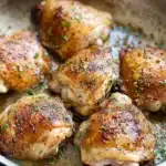 Crispy garlic brown sugar chicken thighs in skillet with herbs