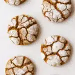 Chewy gingerbread crinkle cookies with powdered sugar on a baking surface