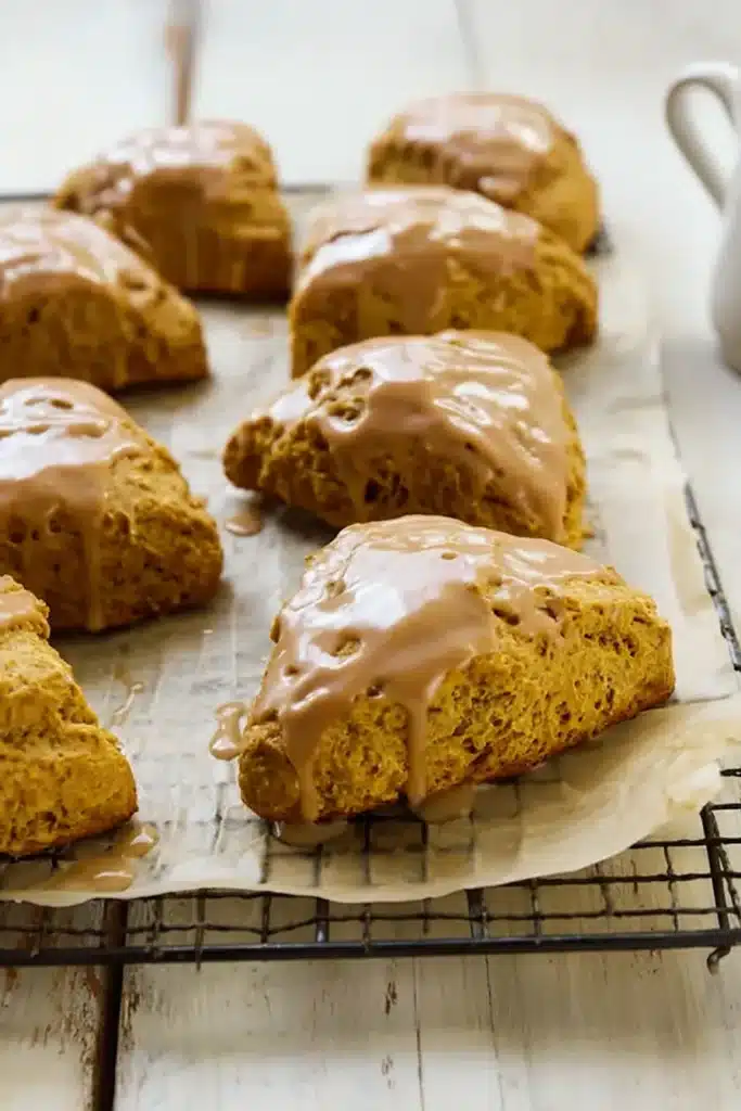 Pumpkin scones with spiced glaze cooling on wire rack
