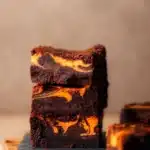 Fudgy Halloween brownies with orange cheesecake swirl on a wooden board