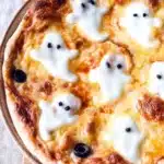 Halloween Ghost Pizza – Easy, Fun, and Spooky 10 Halloween ghost pizza with melted mozzarella ghosts and olive eyes on golden crust