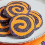 Halloween pinwheel cookies with orange and black swirls on a white plate