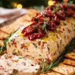 Italian cheese log with sun dried tomatoes, herbs, and crackers for Christmas appetizer