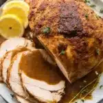 Juicy Slow Cooker Turkey Breast – Simple & Sensational 14 Juicy slow cooker turkey breast with crispy skin and gravy on a white plate with lemon and thyme