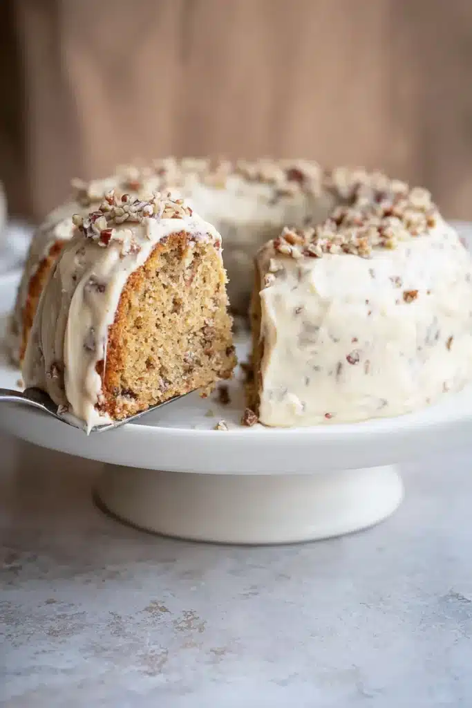 Keto Butter Pecan Pound Cake – Moist, Nutty & Delicious 9 Slice being lifted from keto butter pecan pound cake with frosting