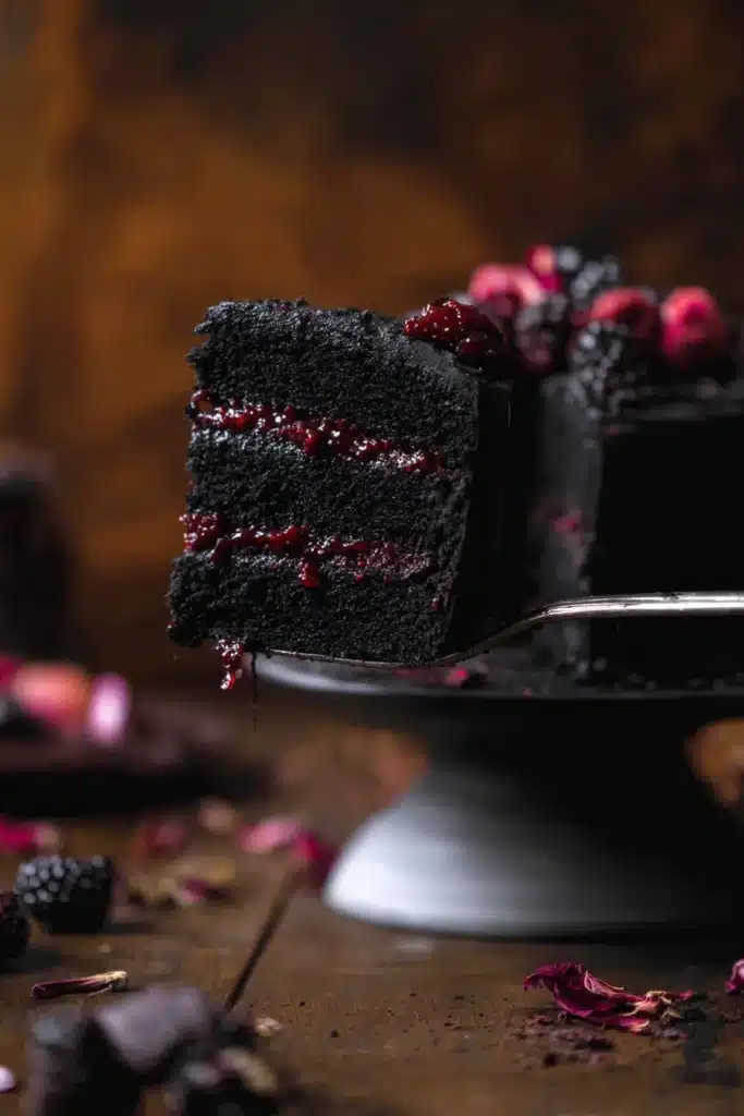 Spooky Black Velvet Halloween Cake slice showing berry filling on cake server