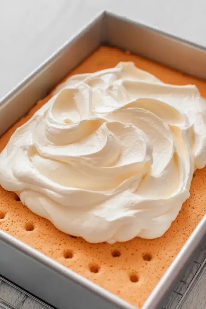 Orange Creamsicle Cake Recipe – Simple & Refreshing Treat 27 Orange creamsicle cake with whipped topping ready to spread