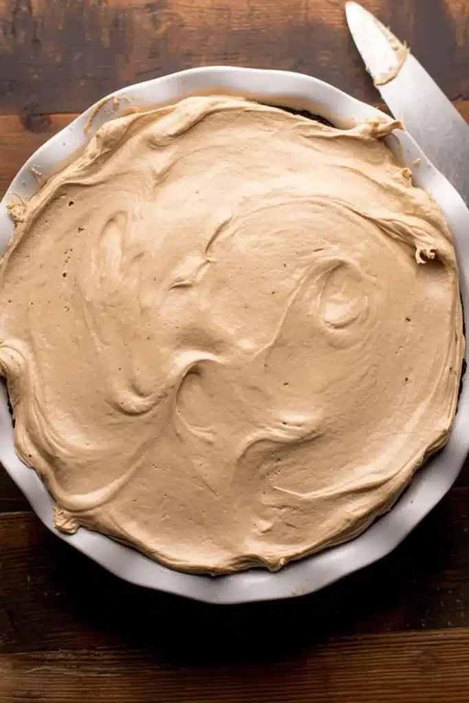 Peanut butter layer smoothed into pie dish for no-bake chocolate peanut butter pie
