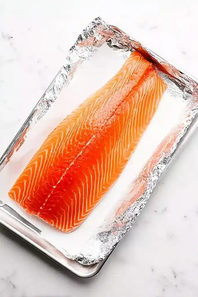 Raw side of salmon on foil and parchment ready for baking