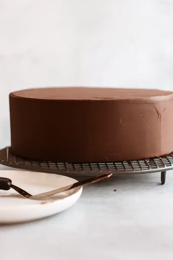 Smoothly frosted chocolate cake on a wire rack, ready for mirror glaze