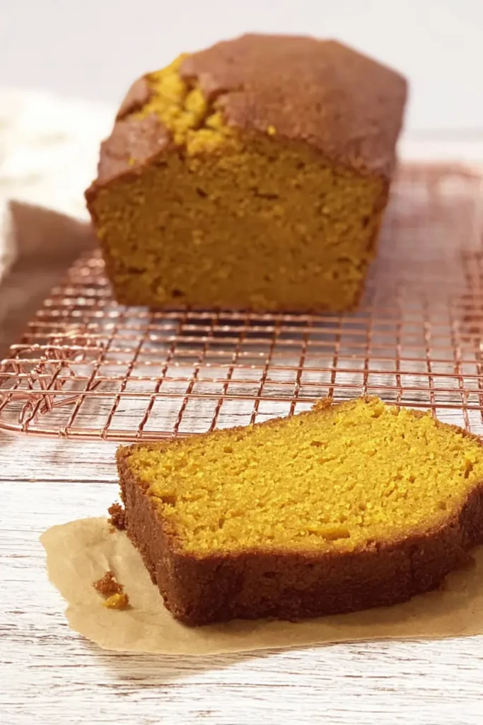 Pumpkin Bread – Rich, Moist & Irresistible Fall Favorite 13 Baked pumpkin bread loaf cooling with a sliced piece in the foreground