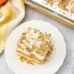 Pumpkin lush dessert slice with whipped topping and pecans on a white plate