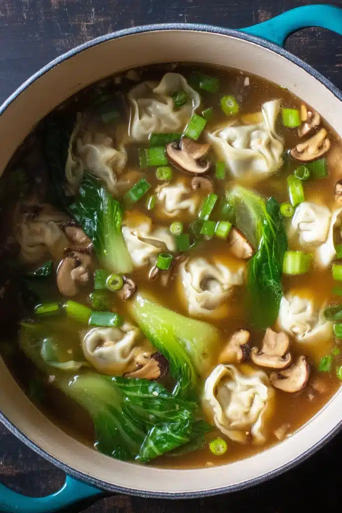 Quick & Easy Wonton Soup finished in a Dutch oven with greens and mushrooms