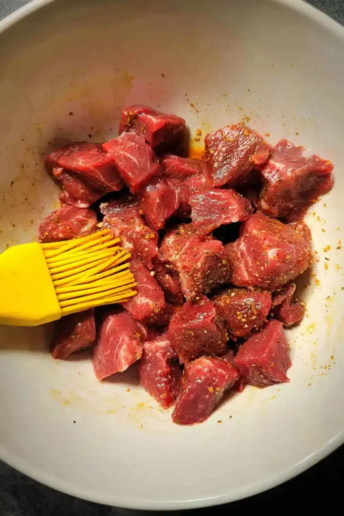 Raw garlic butter air fryer steak bites being prepped in mixing bowl