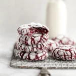 Stack of red velvet crinkle cookies with powdered sugar on a wire rack