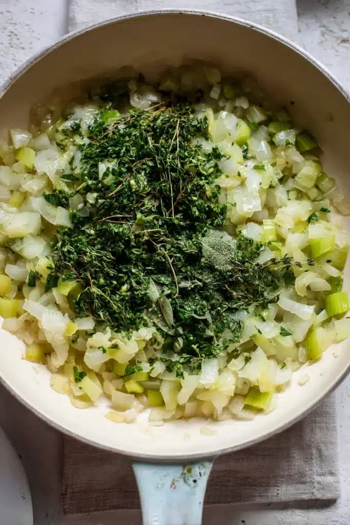 Our Favorite Buttery Herb Stuffing | Ultimate Holiday Side 14 Soft sautéed onions and celery with fresh herbs in cream skillet