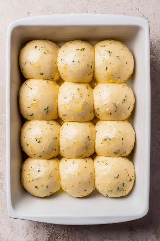 Risen dough for easy garlic bread rolls in white baking dish