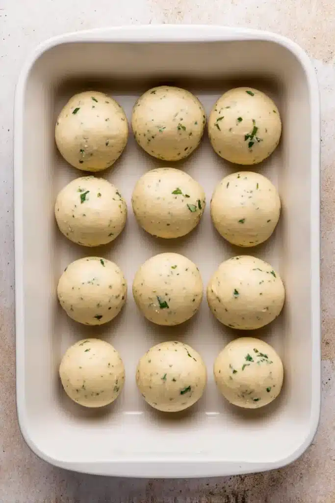Shaped easy garlic bread rolls dough balls in white baking dish